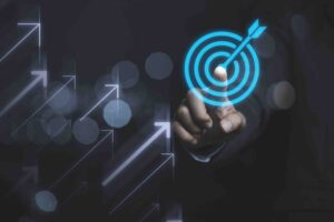 This image shows a business success concept: a person in a suit points at a glowing target with an arrow hitting the bullseye.