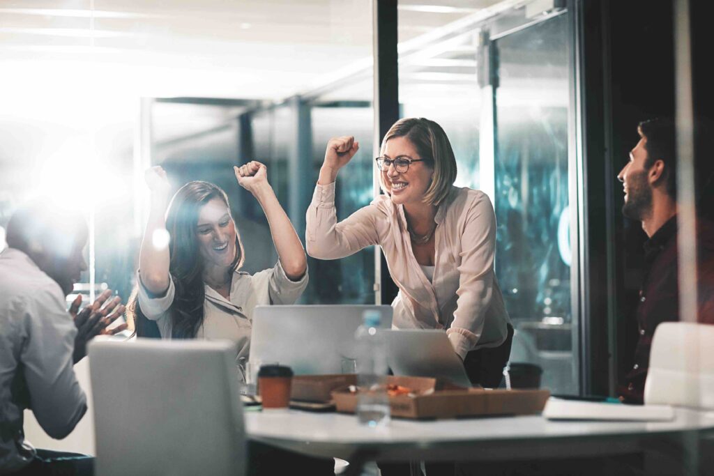 This image shows coworkers in a modern office celebrating during a meeting.