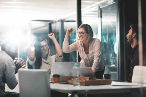 This image shows coworkers in a modern office meeting room celebrating together.