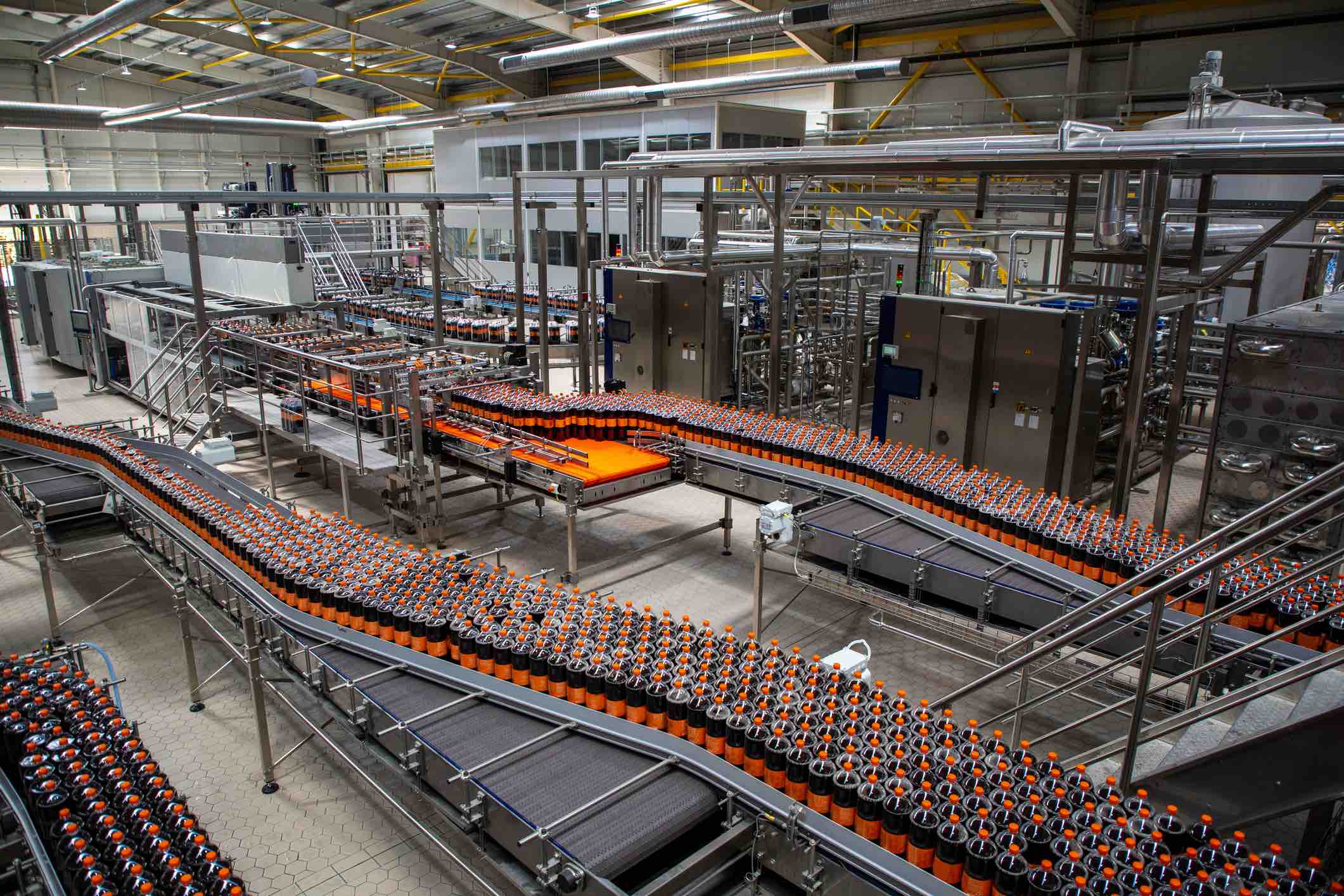 Production line of bottled ice tea beverage moving on conveyor belt in factory