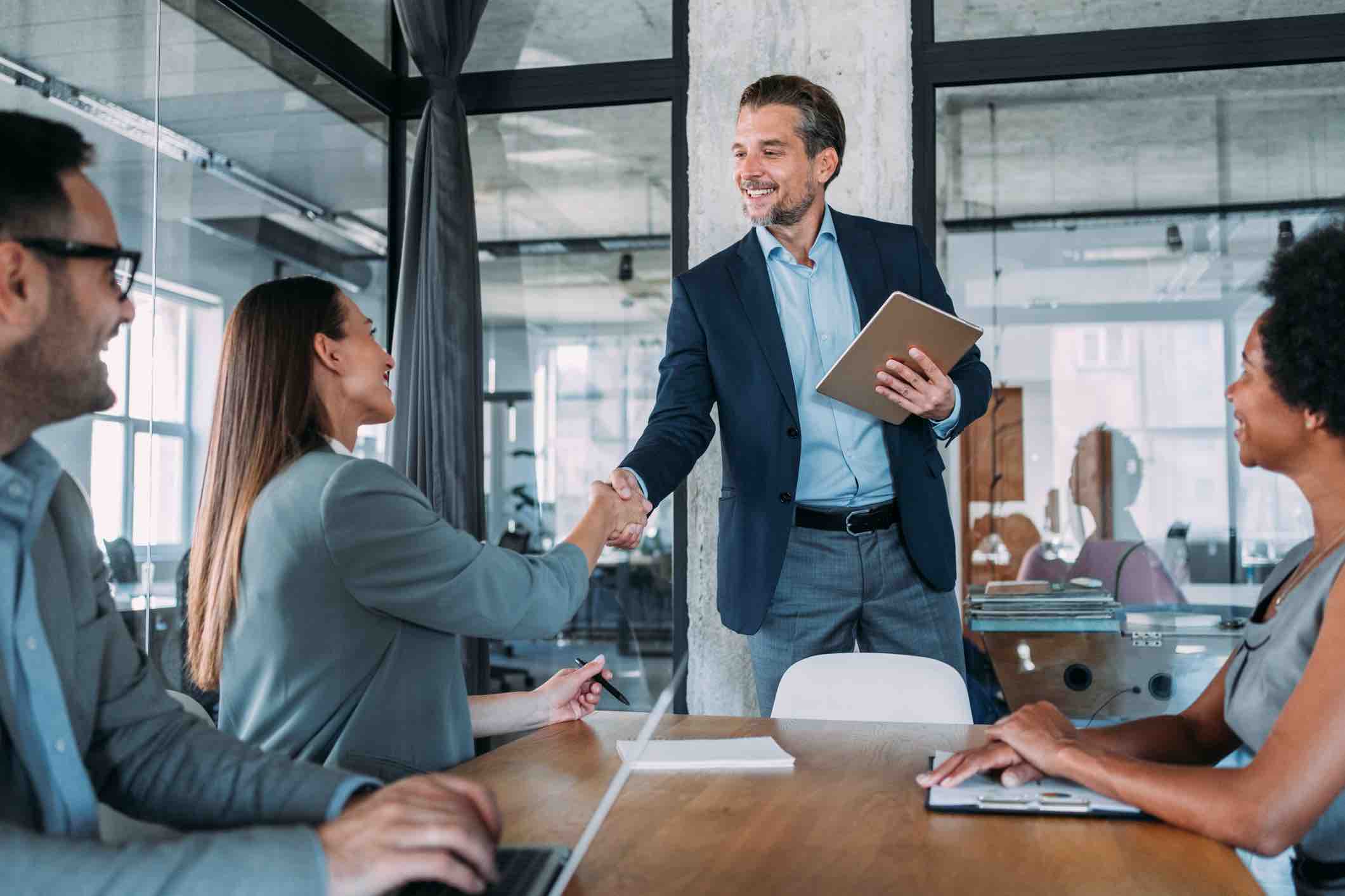Businesswoman and businessman shaking hands across the table.